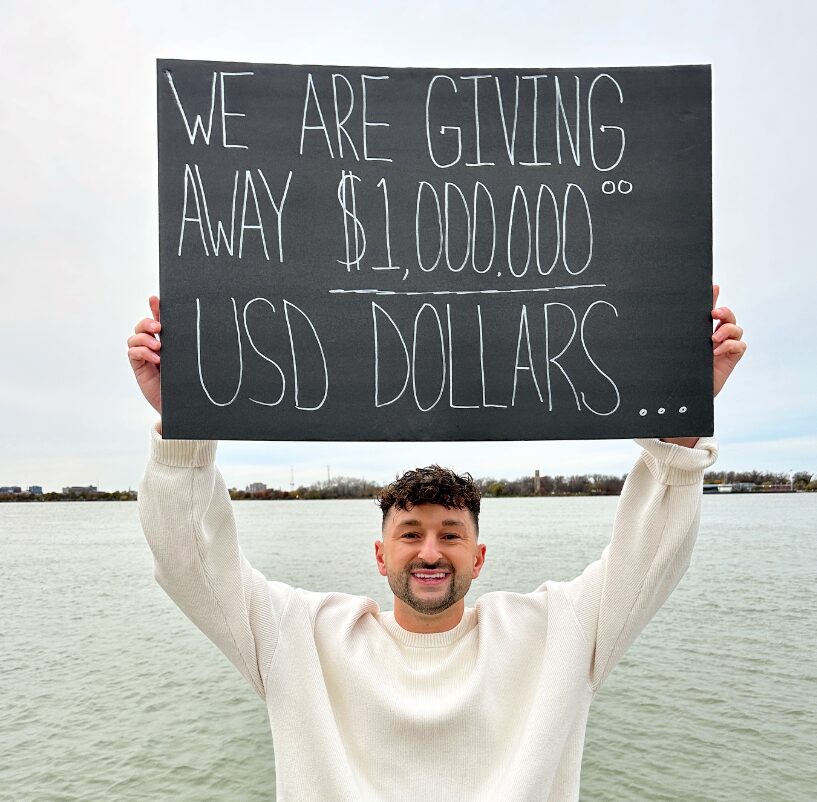 Zachery Dereniowski holding a sign reading We Are Giving Away $1,000,000 USD