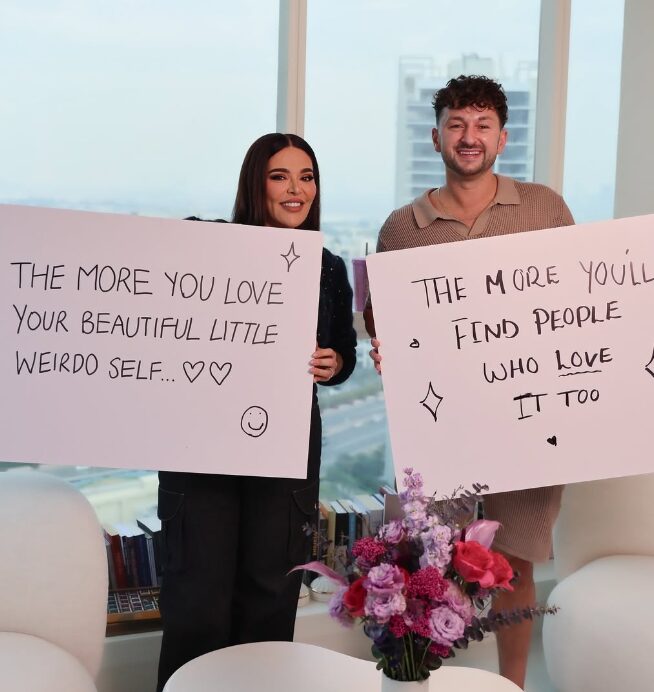 Two people holding handwritten kindness affirmation signs