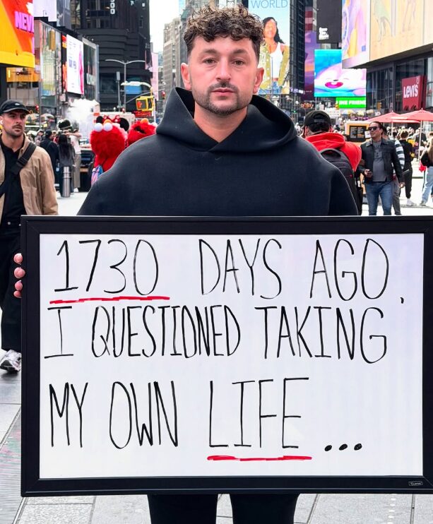 Zachery in Times Square holding a sign about surviving his own mental health crisis