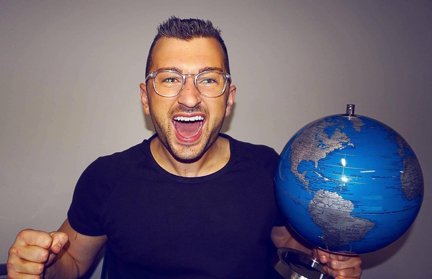 A joyful Zachery Dereniowski holding a globe